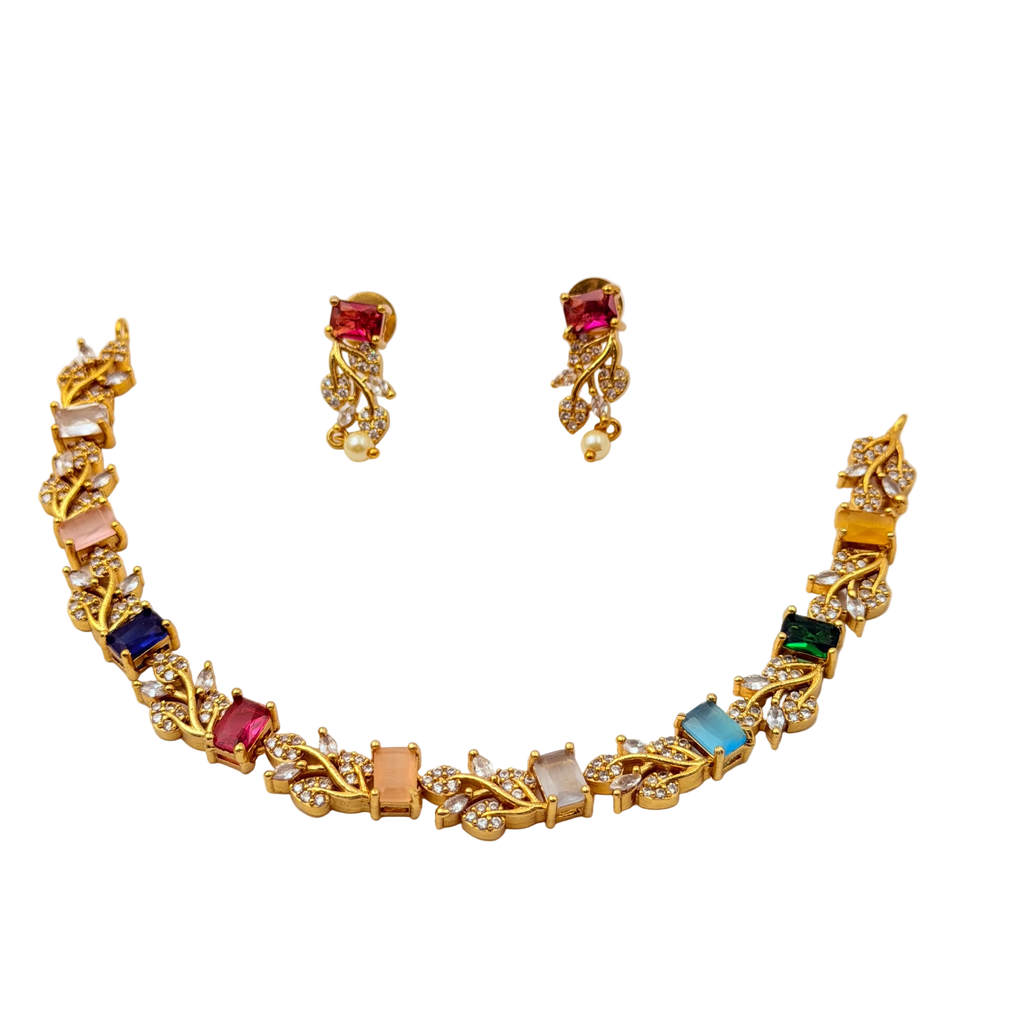Gold necklace and earrings set with multicolored gemstones on a white background