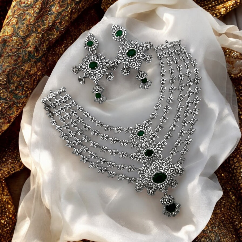 Silver-tone emerald & white stone multi-layered necklace set with earrings, flat-lay on cream festive fabric