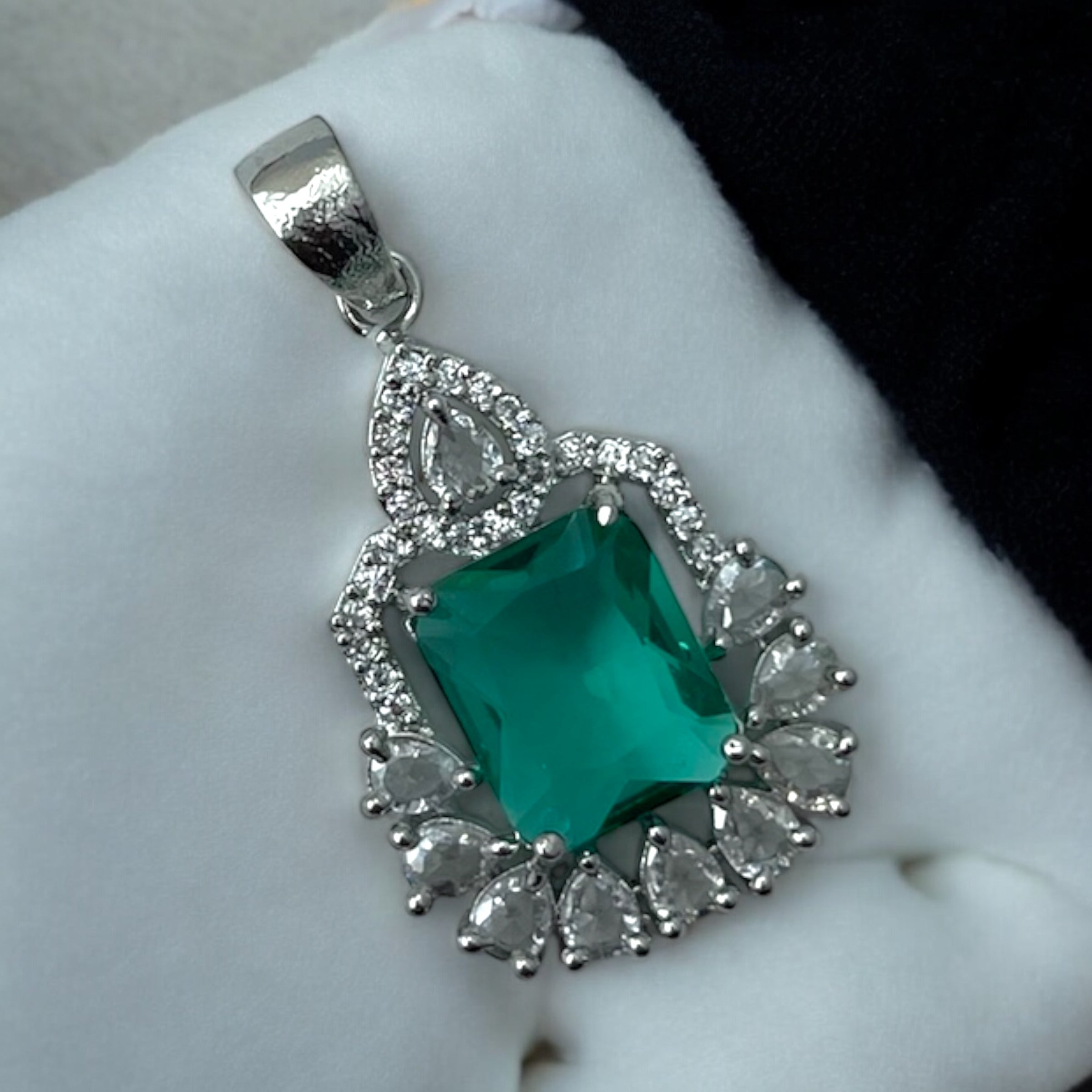 Silver-tone green emerald-cut halo pendant with CZ accents, worn on a model with a navy saree