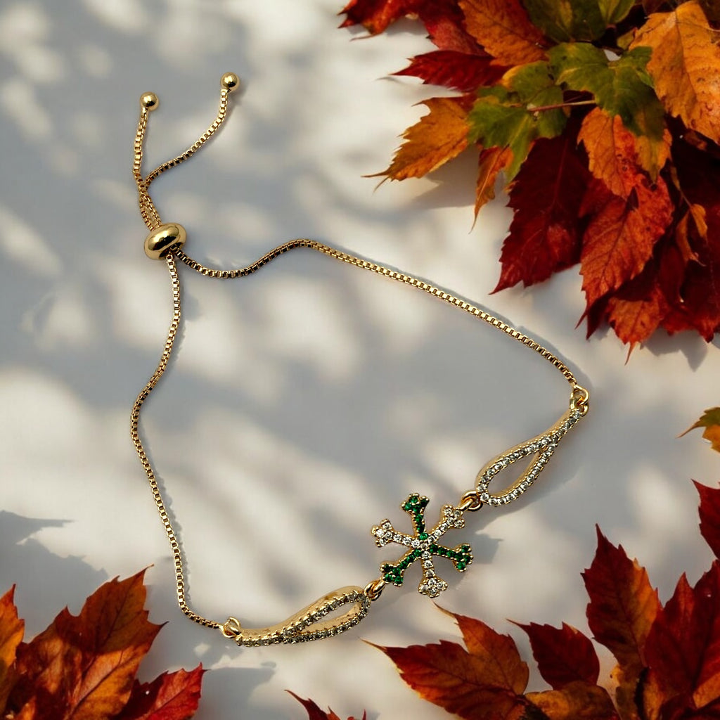 Gold-toned trident bracelet with green and white CZ stones on adjustable chain, worn on wrist poolside