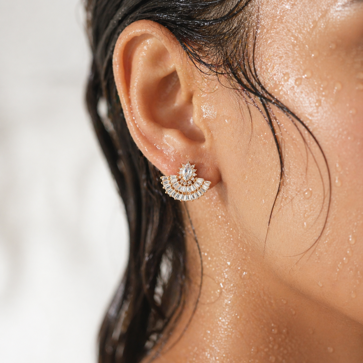 Close-up of an ear wearing a diamond earring with a blurred background