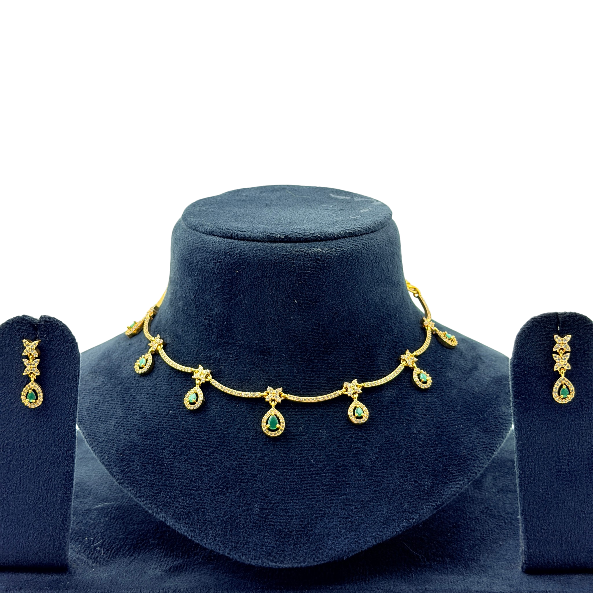 Gold necklace with green gemstones on a blue velvet stand, accompanied by matching earrings.