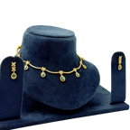 Gold necklace with green gemstones on a blue velvet stand, accompanied by matching earrings.
