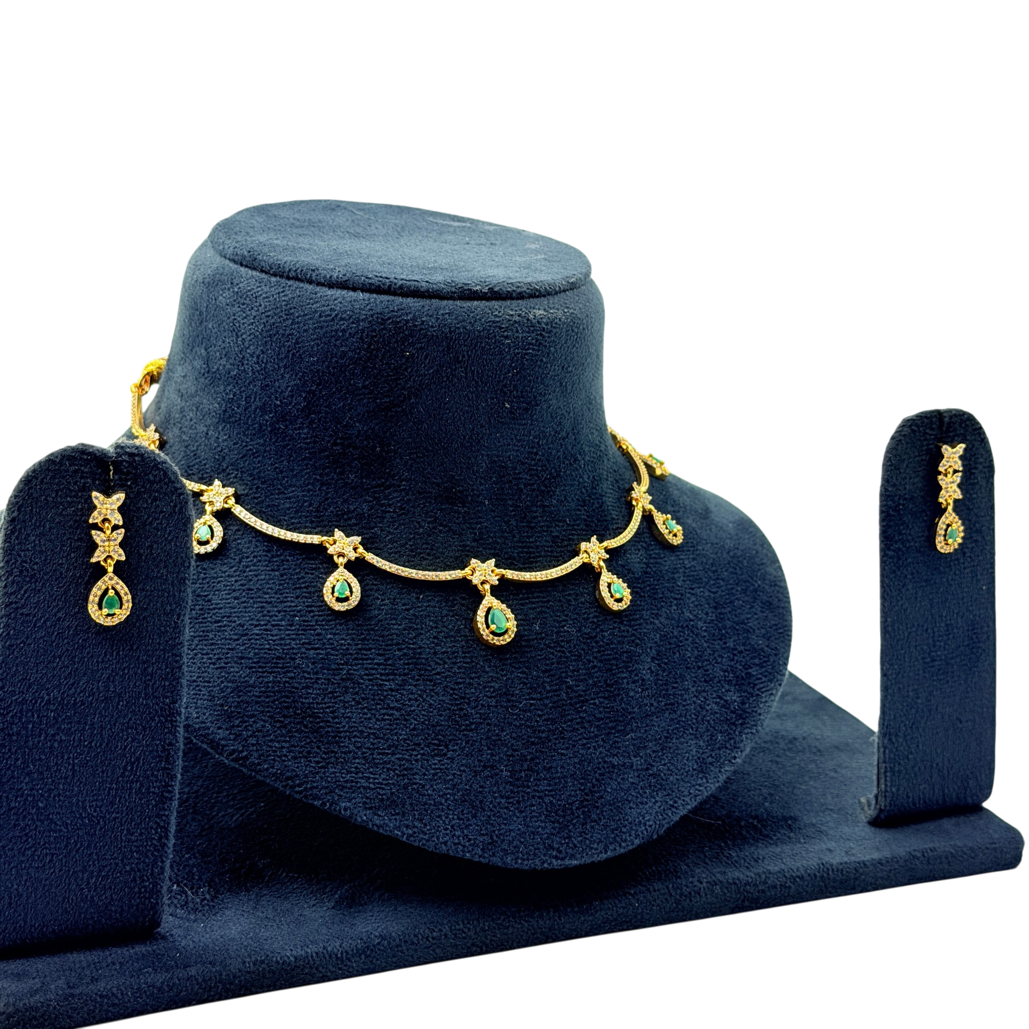 Gold necklace with green gemstones on a blue velvet stand, accompanied by matching earrings.