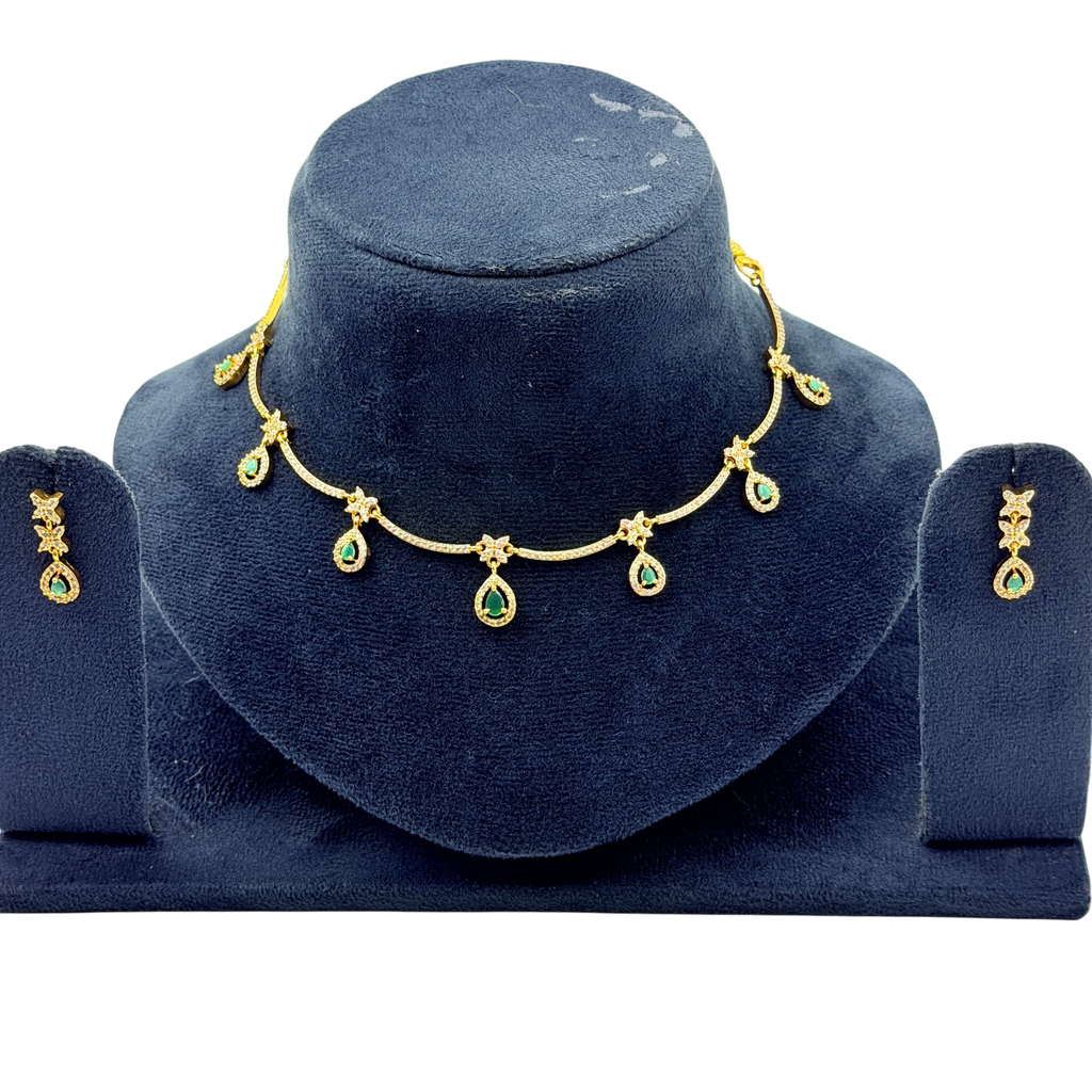 Gold necklace with green gemstones on a blue velvet stand