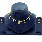 Gold necklace with green gemstones on a blue velvet stand