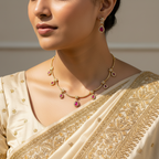 Woman wearing a gold necklace and earrings with a beige saree.