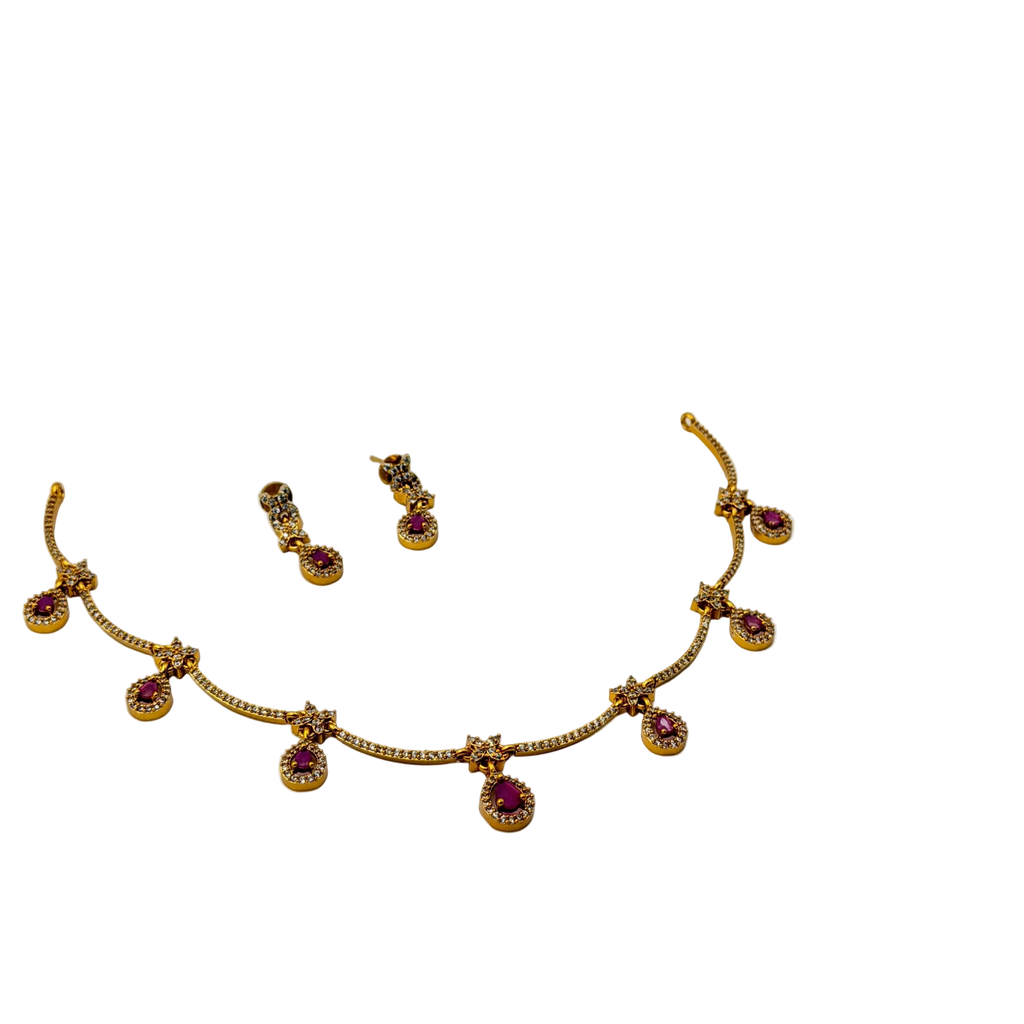 Gold necklace with red gemstones and matching earrings on a white background