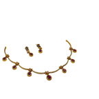 Gold necklace with red gemstones and matching earrings on a white background