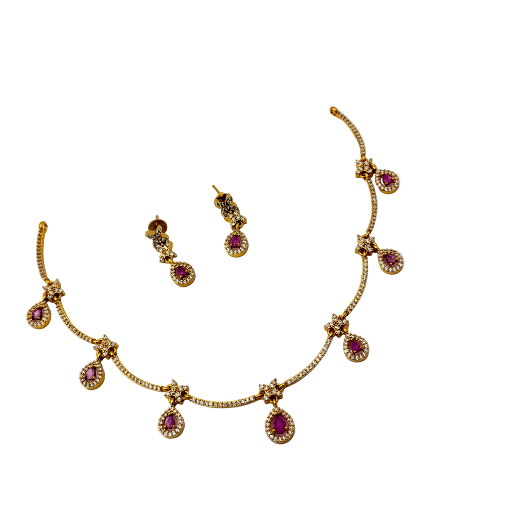 Gold necklace with red gemstones and matching earrings on a white background