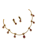 Gold necklace with red gemstones and matching earrings on a white background