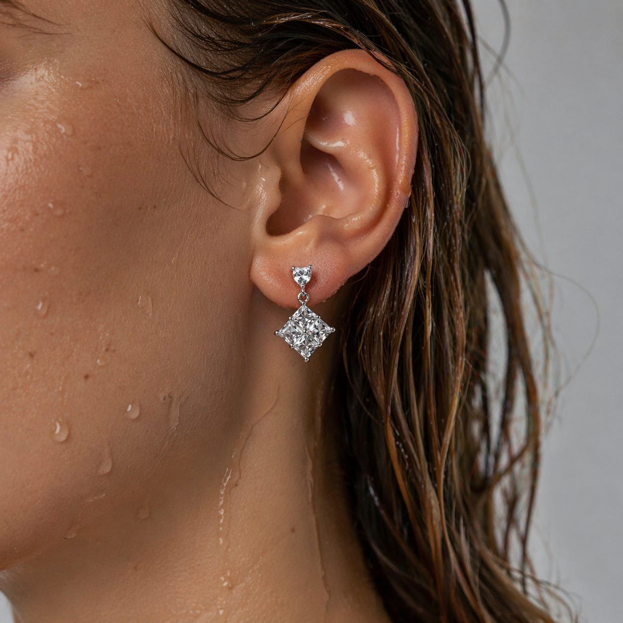 Close-up of an ear wearing a diamond earring with water droplets on skin