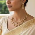 Woman wearing a gold necklace and earrings with a beige saree.