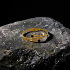 Gold ring with black stones on a dark stone surface
