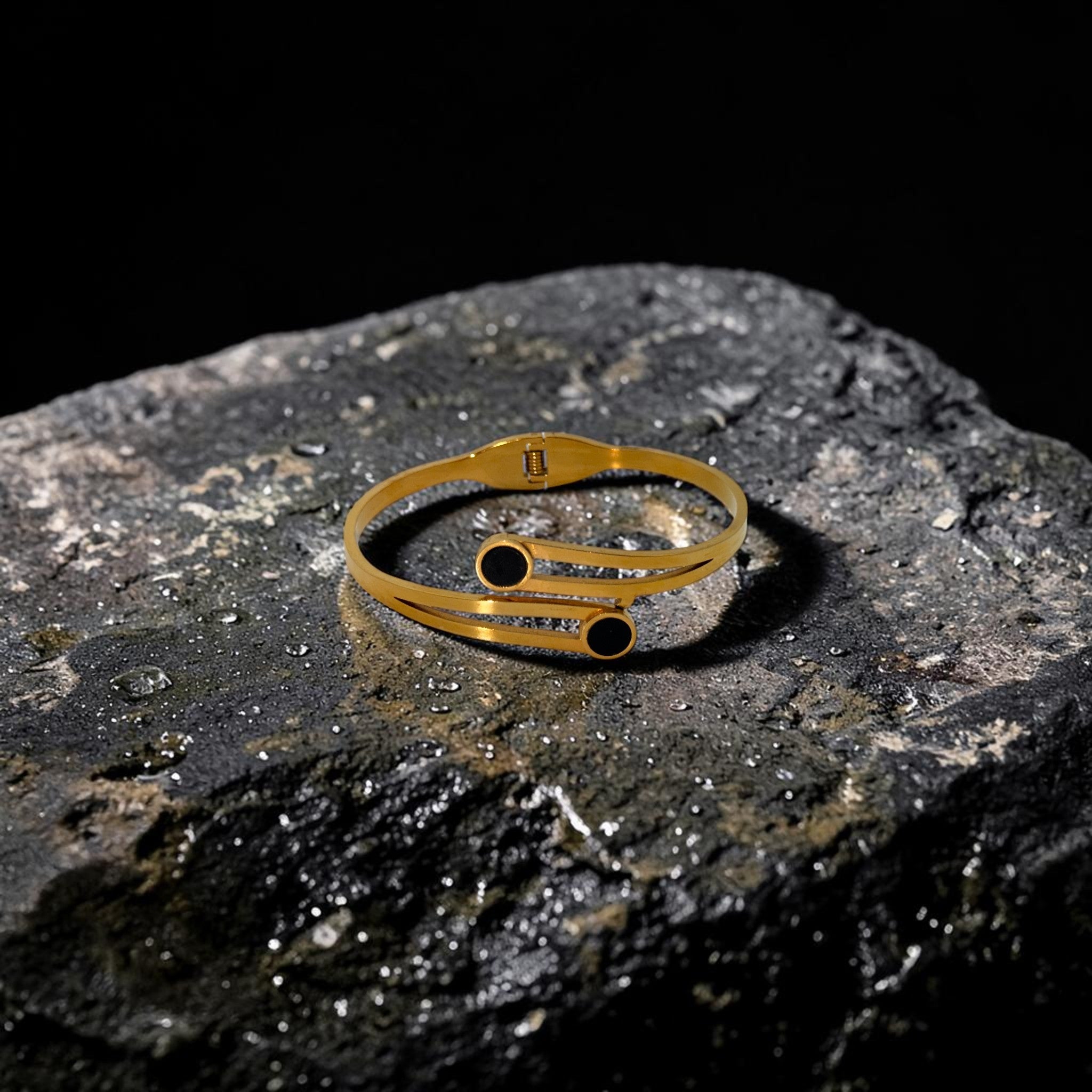 Gold ring with black stones on a dark stone surface