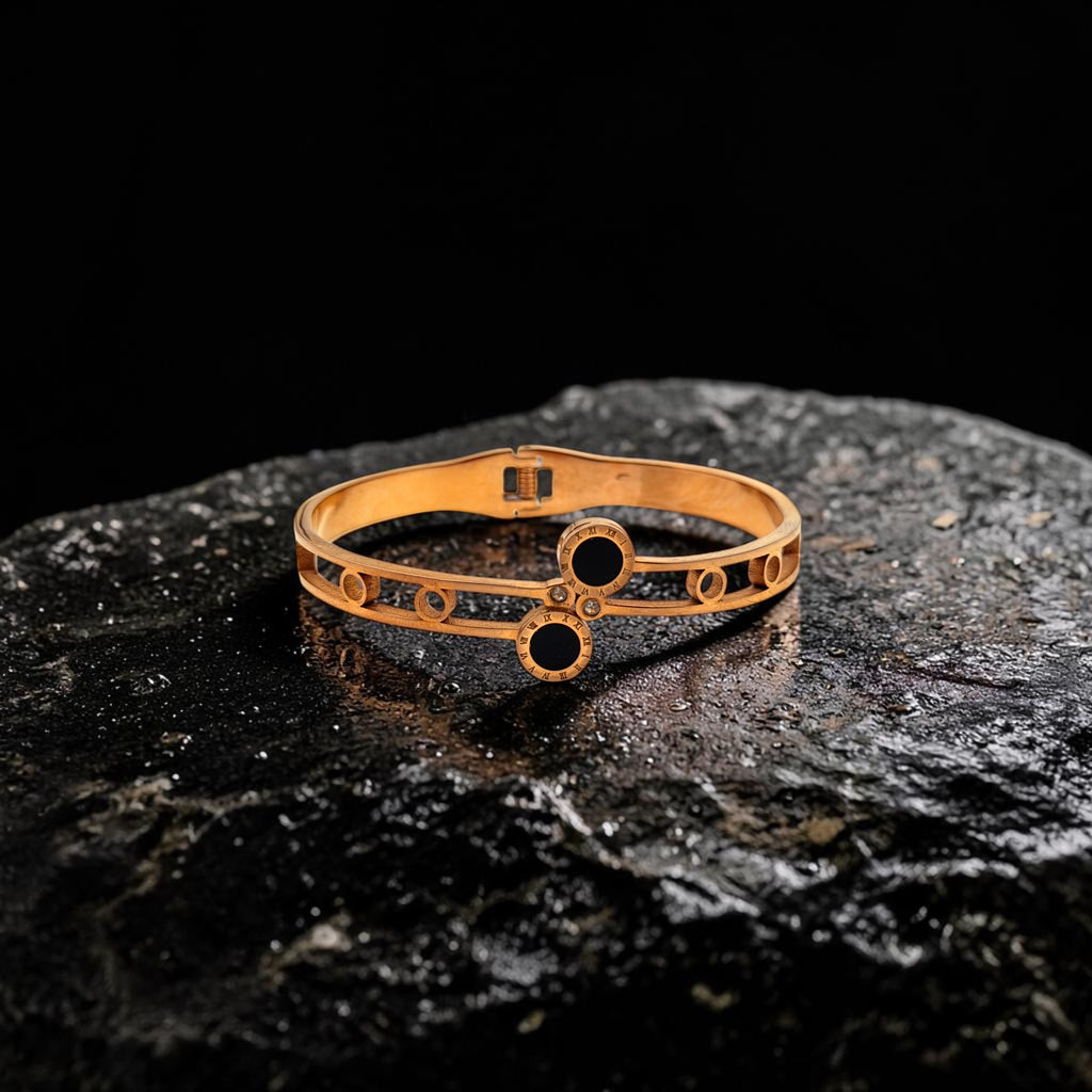 Gold bracelet with black stones on a dark stone surface