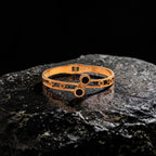 Gold bracelet with black stones on a dark stone surface
