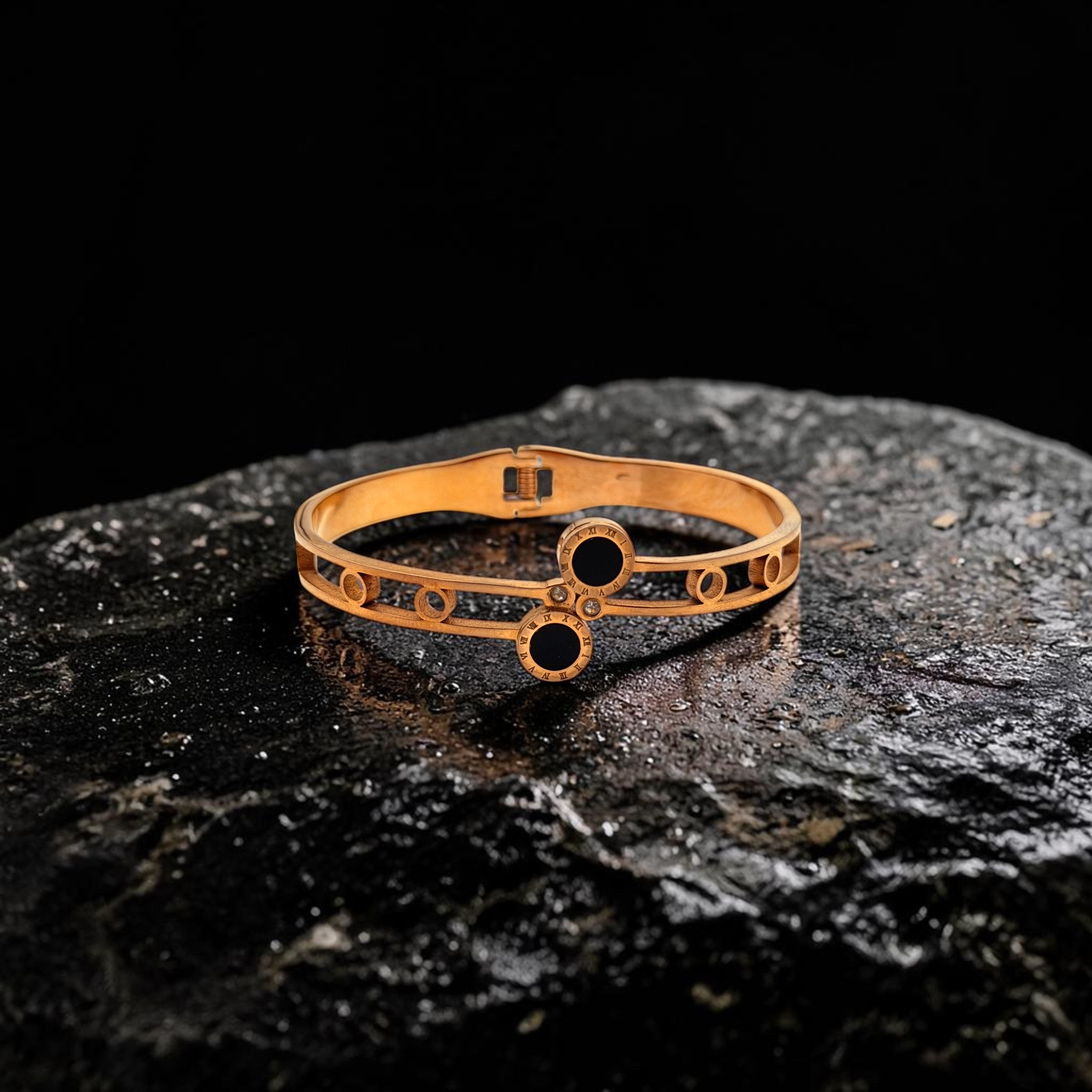 Gold bracelet with black stones on a dark stone surface