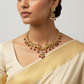 Woman wearing a gold necklace and earrings with a plain background