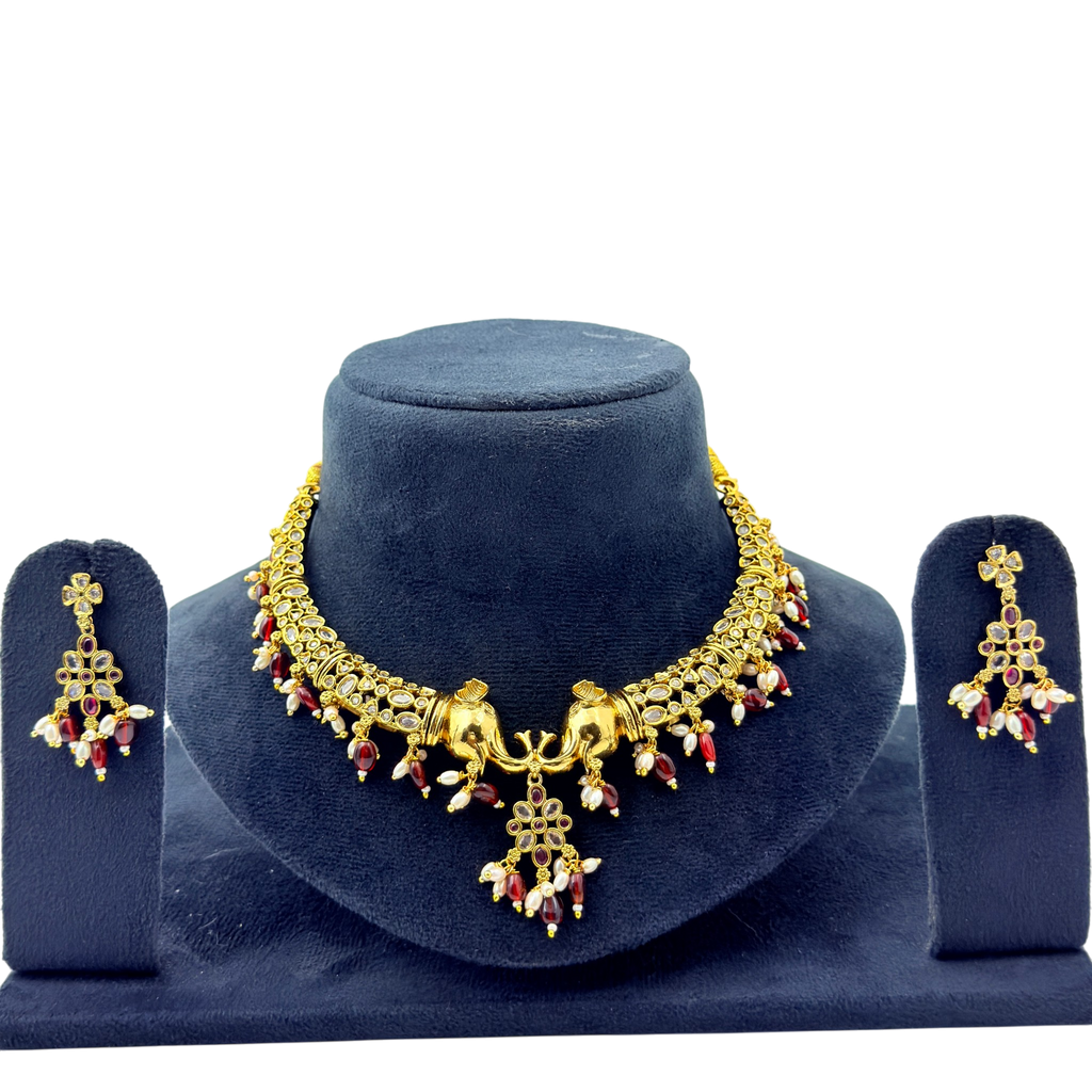 Gold necklace and earrings set on a blue velvet stand with a white background