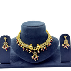 Gold necklace and earrings set on a blue velvet stand with a white background