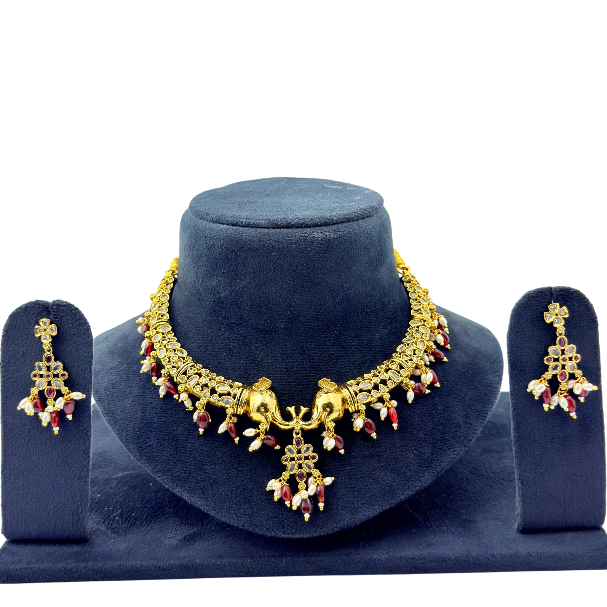 Gold necklace and earrings set on a blue velvet stand with a white background