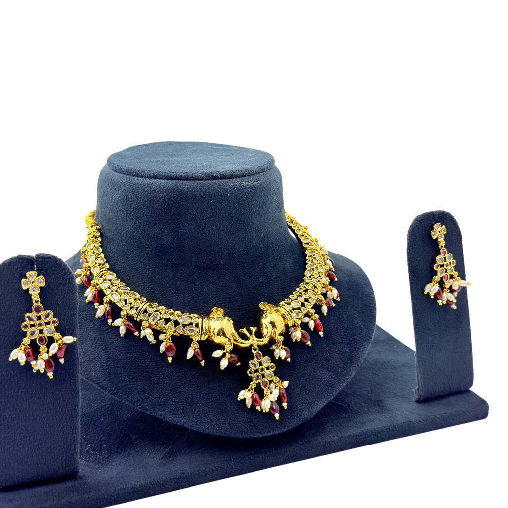 Gold necklace and earrings set on a blue velvet stand