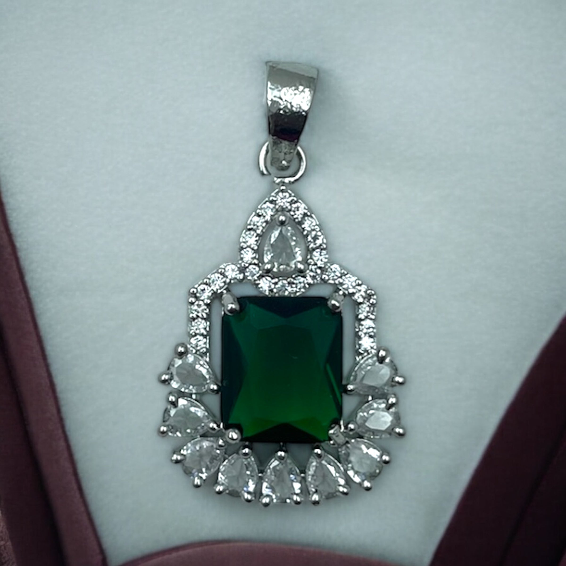 Silver-tone emerald-green halo pendant with CZ accents, worn on a model with a saree