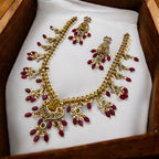 Gold-plated Lakshmi temple necklace and earrings set with ruby drops and pearls, displayed in a wooden gift box