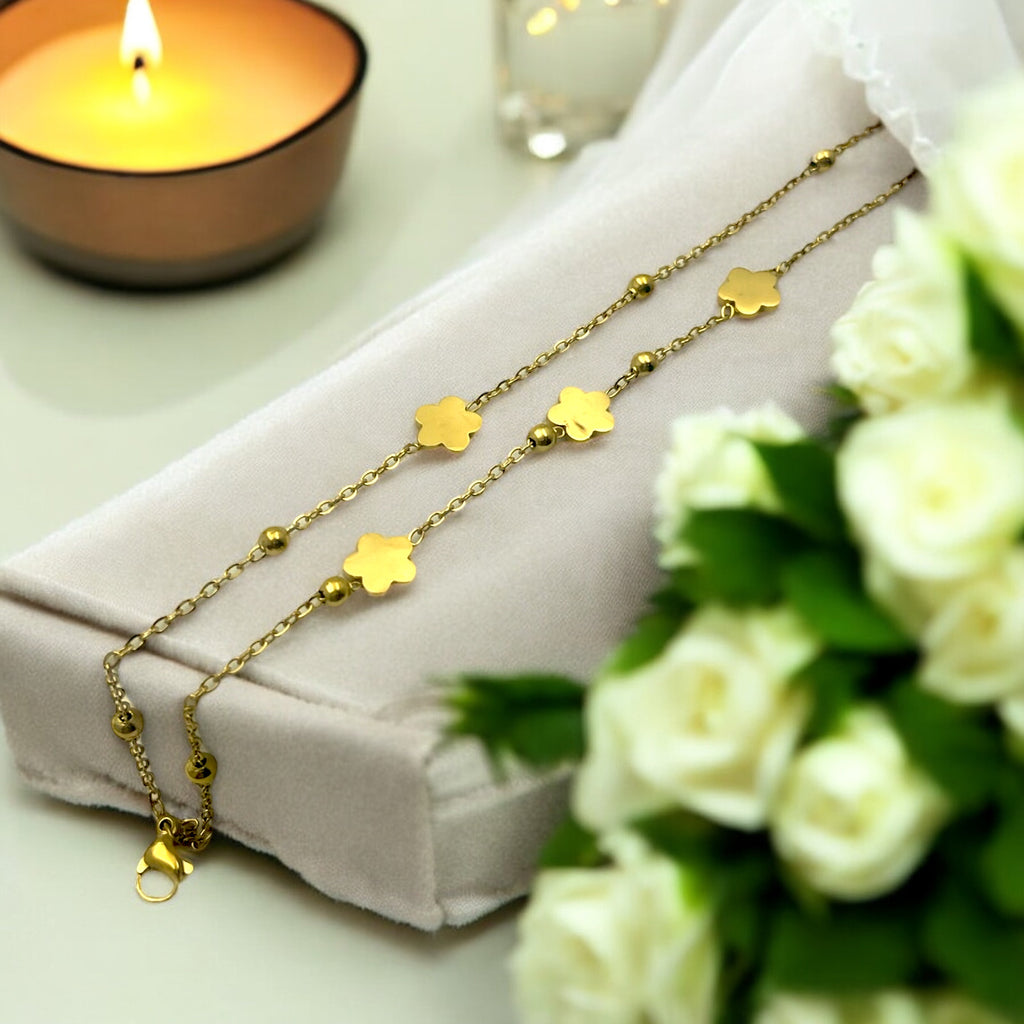 Gold-toned double-chain bracelet with flower charms and beads, worn on wrist poolside