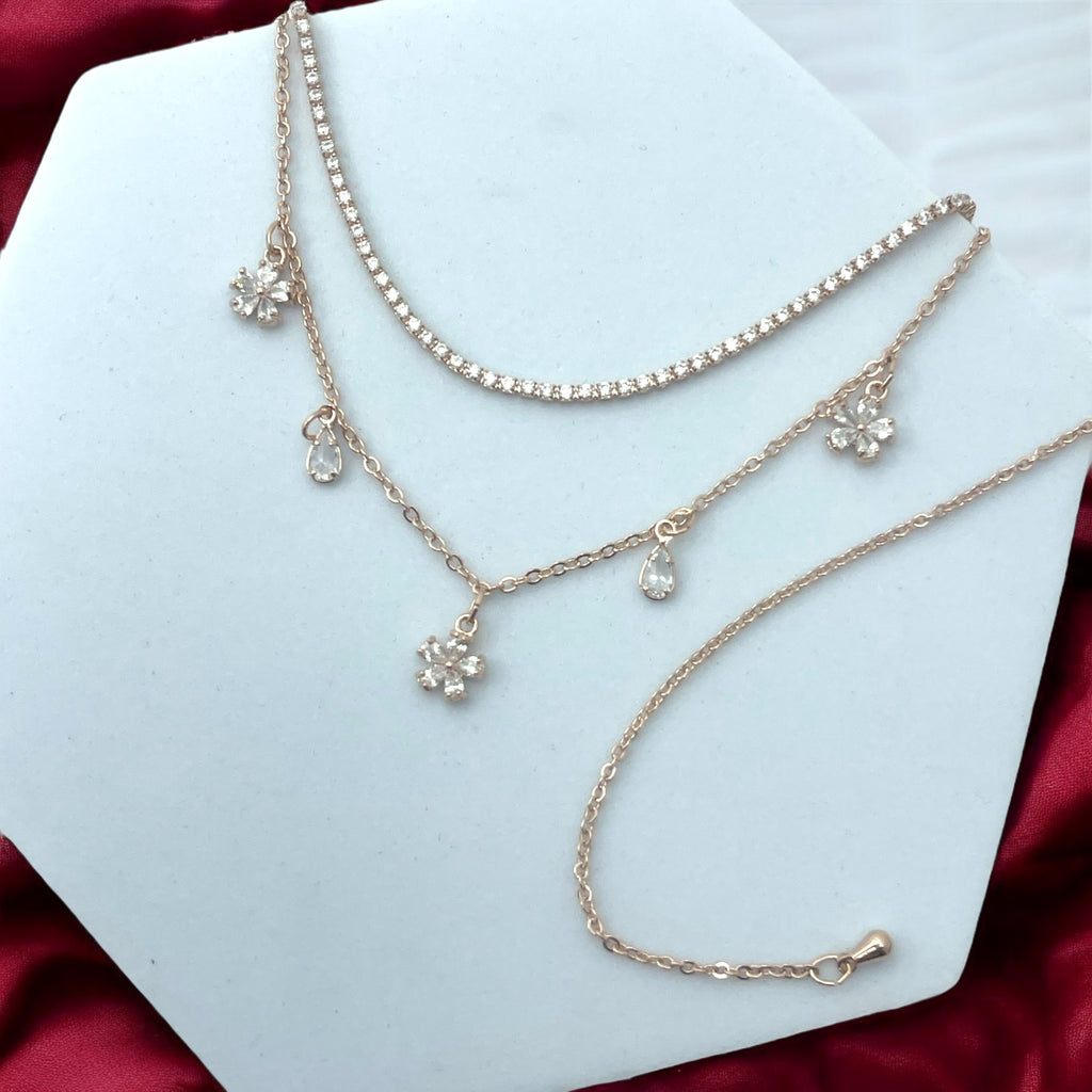 Rose gold layered choker with sparkling stone row, floral and teardrop charms, shown on model with matching earrings