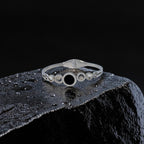 Silver bracelet with circular design on a dark textured surface