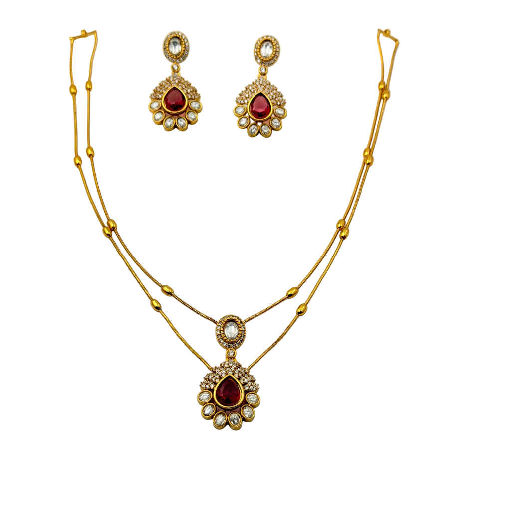 Gold necklace and earrings set with red gemstones on a white background