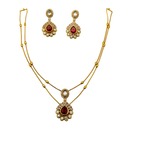 Gold necklace and earrings set with red gemstones on a white background