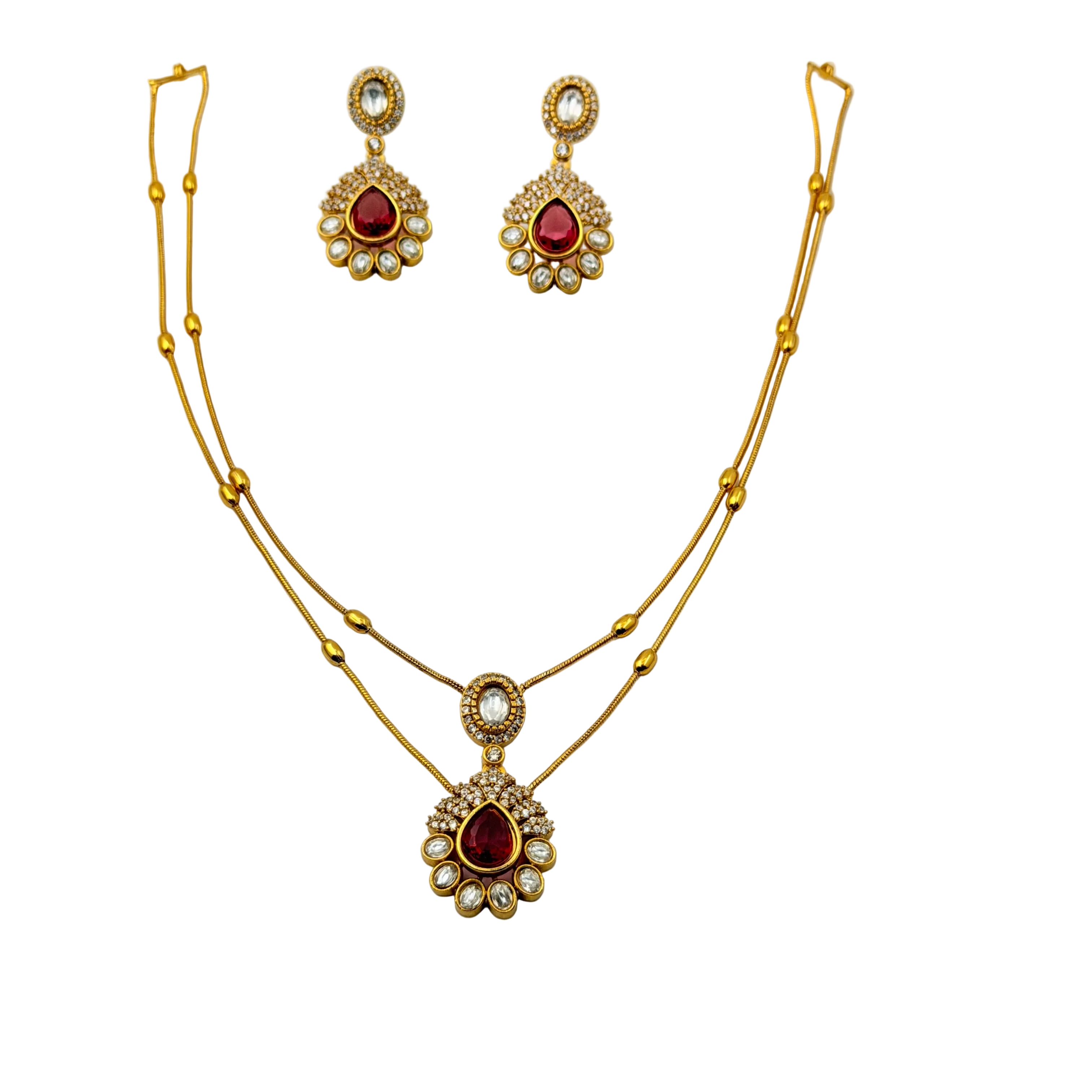 Gold necklace and earrings set with red gemstones on a white background