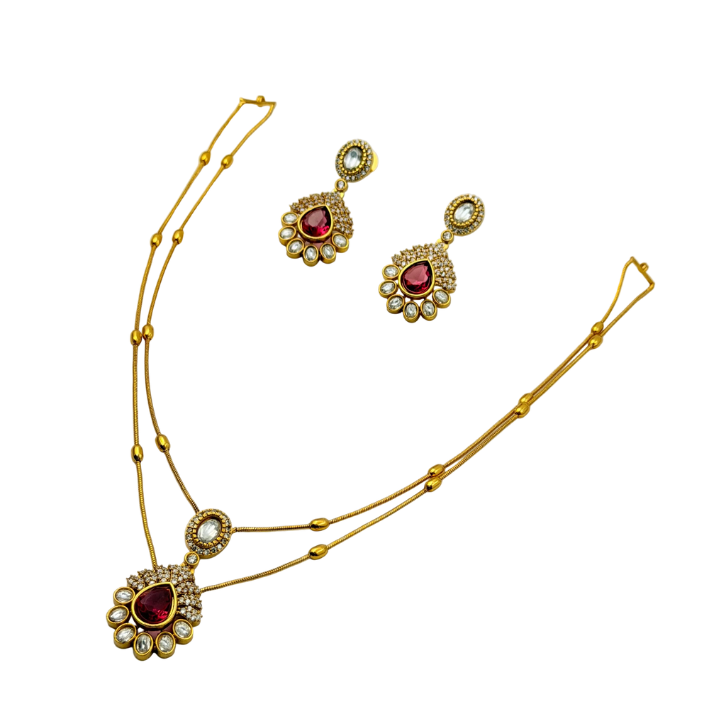 Gold necklace and earrings with red gemstones on a white background