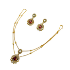 Gold necklace and earrings with red gemstones on a white background