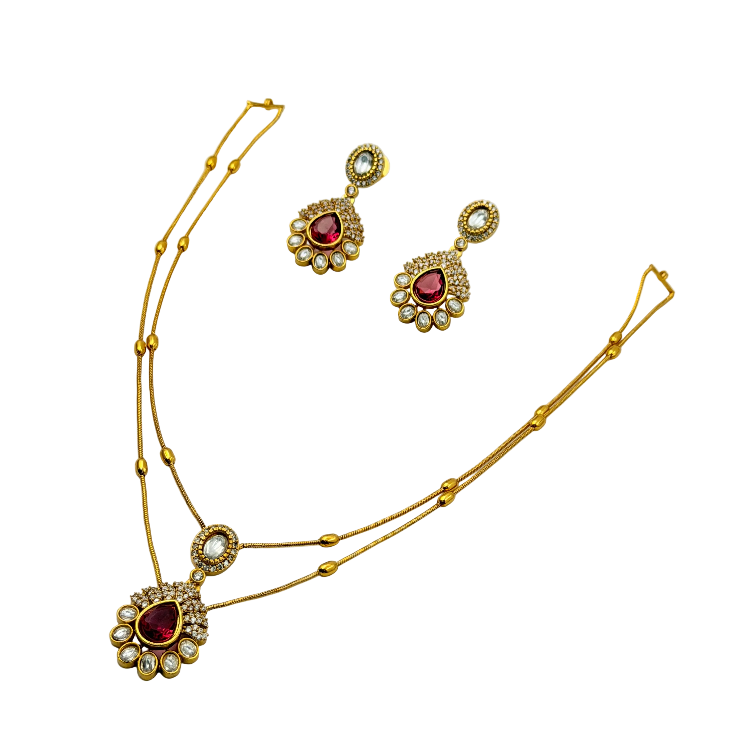 Gold necklace and earrings with red gemstones on a white background