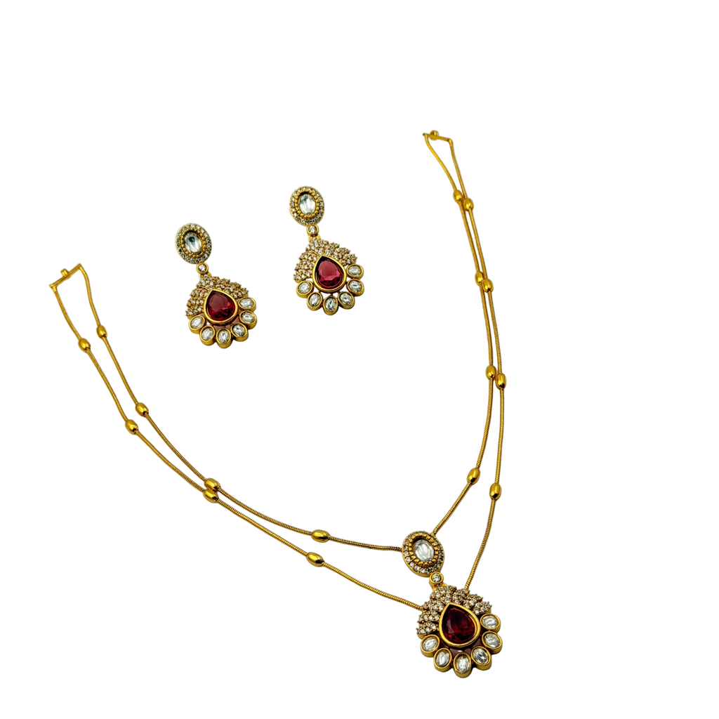 Gold necklace and earrings set with red gemstones on a white background