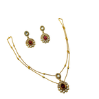 Gold necklace and earrings set with red gemstones on a white background