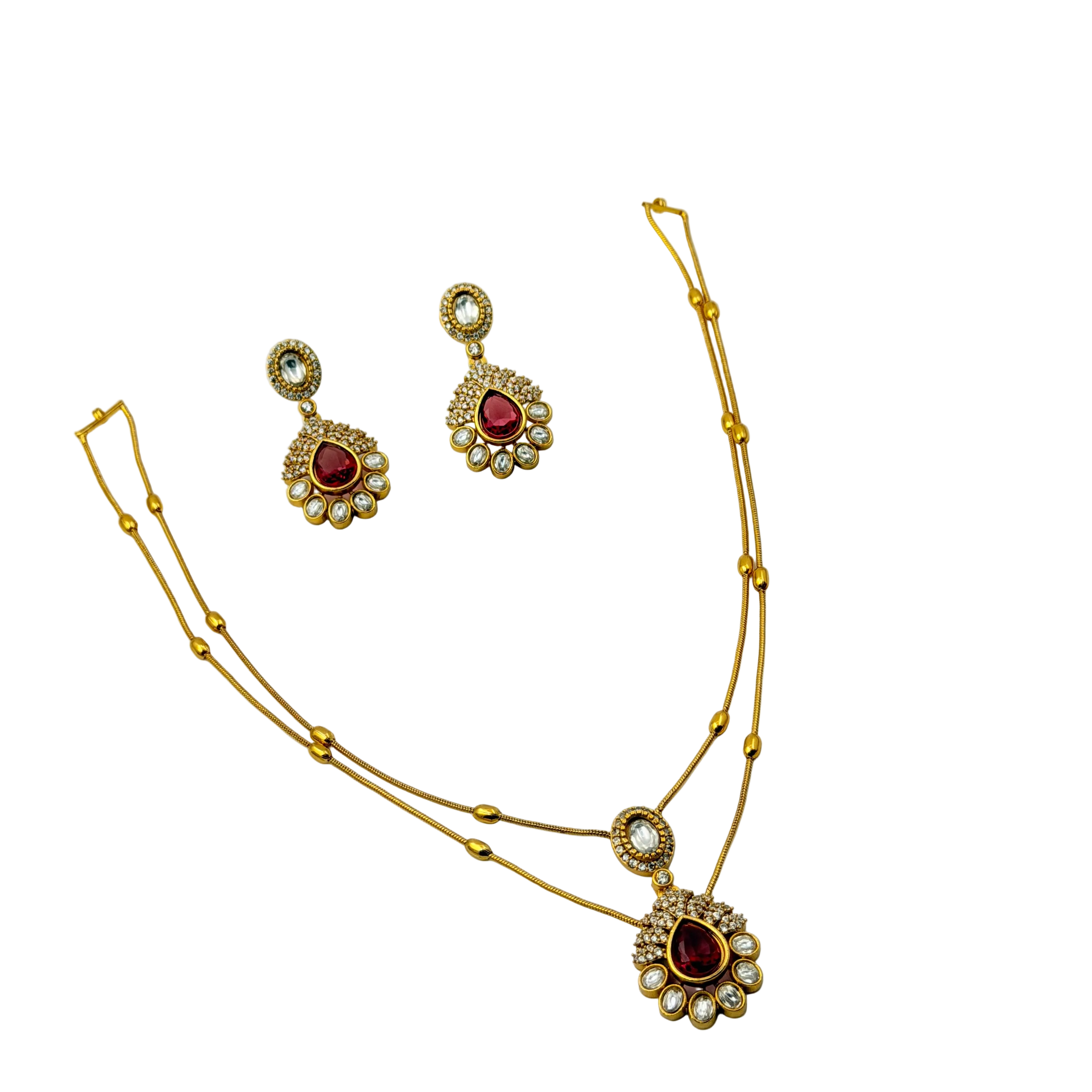 Gold necklace and earrings set with red gemstones on a white background