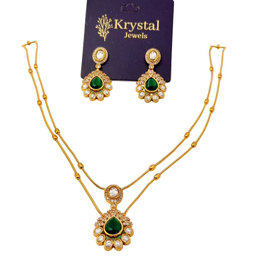 Gold necklace and earrings with green gemstones on a Krystal Jewels card.