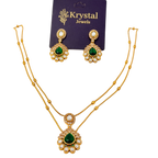 Gold necklace and earrings with green gemstones on a Krystal Jewels card.