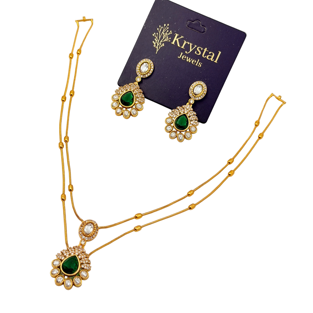 Gold necklace with green gemstones and matching earrings on a Krystal Jewels card.