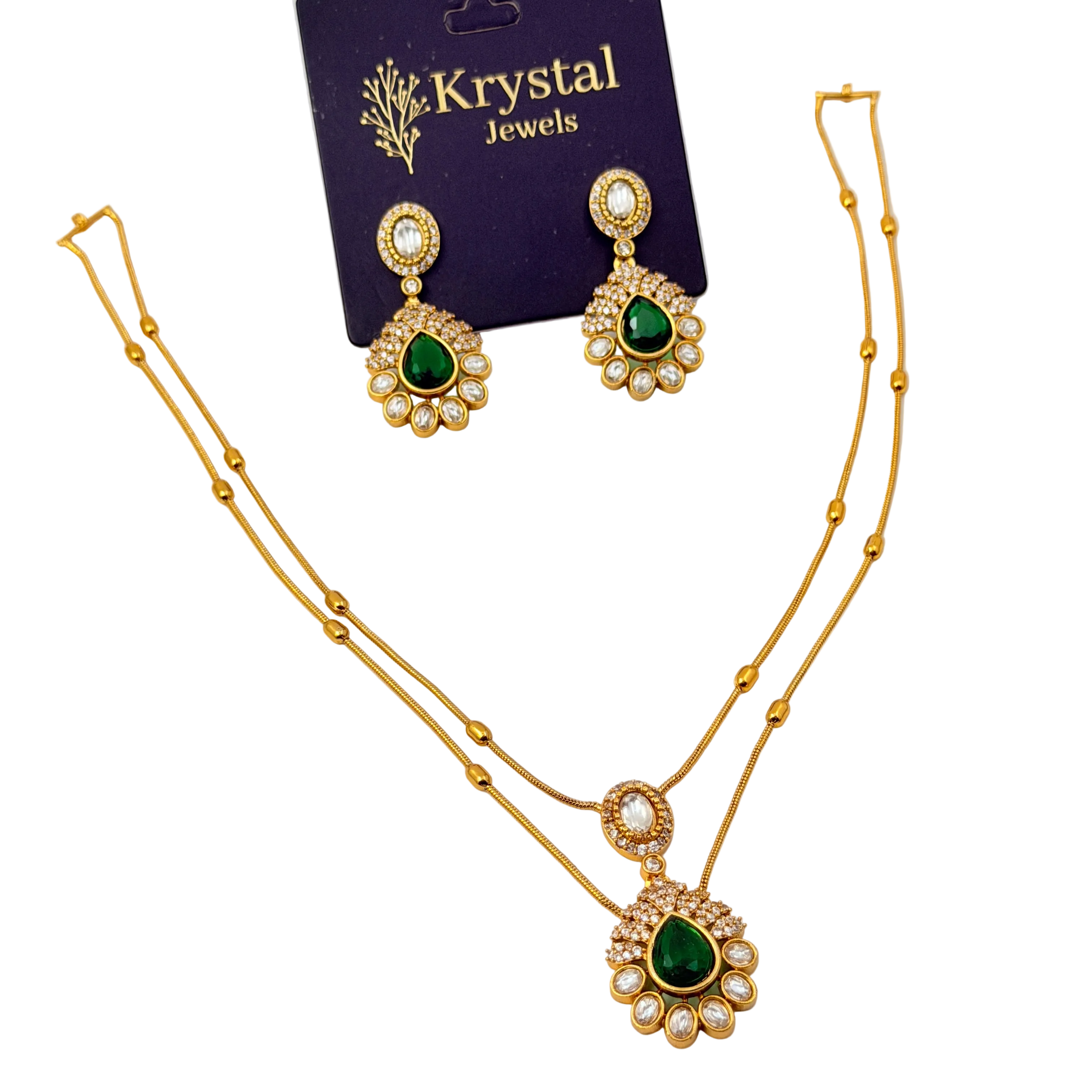 Gold necklace with green gemstones and matching earrings on a Krystal Jewels card.