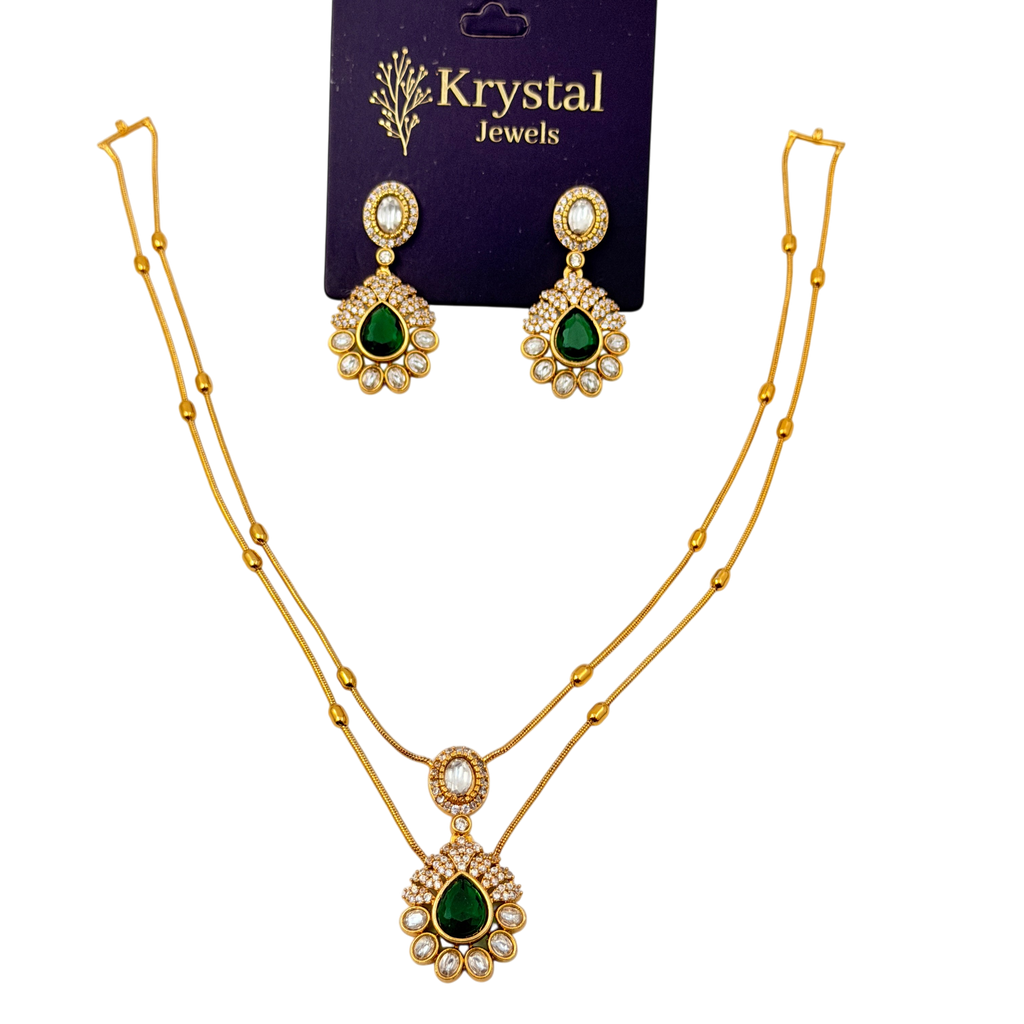 Gold necklace with green gemstones and matching earrings on a Krystal Jewels card.
