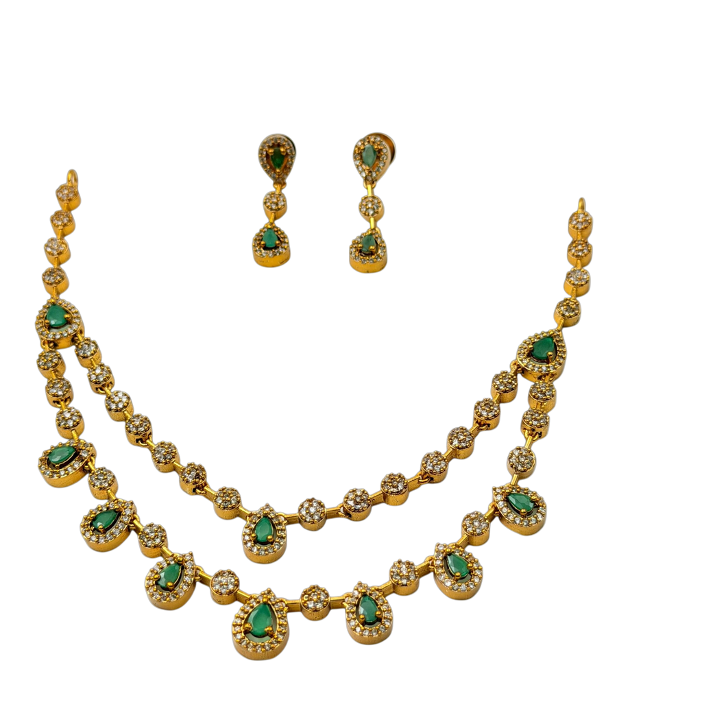 Gold necklace and earrings with green gemstones on a white background