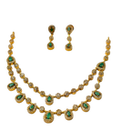 Gold necklace and earrings with green gemstones on a white background