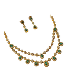 Gold necklace with green gemstones and matching earrings on a black background