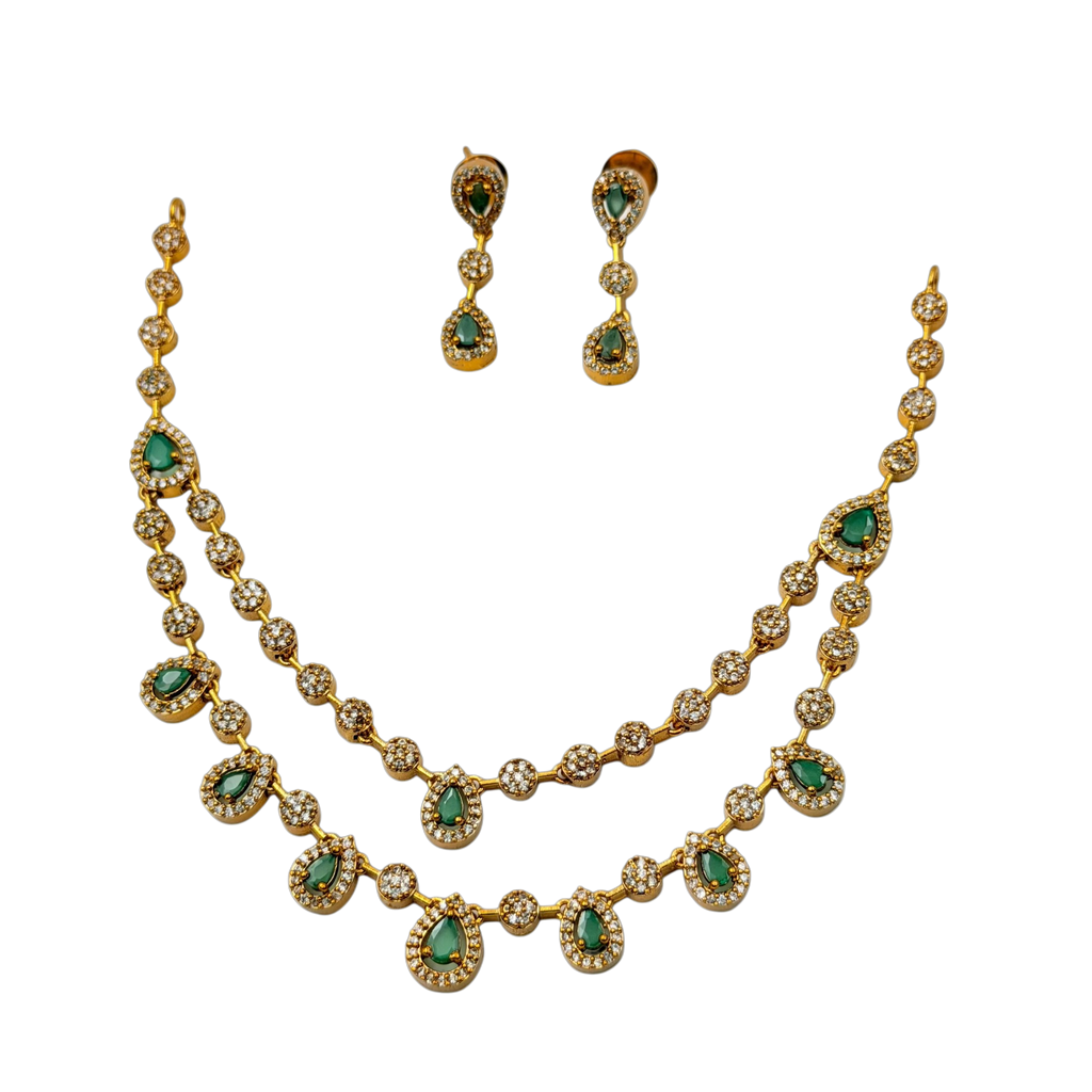 Gold necklace with green gemstones and matching earrings on a white background